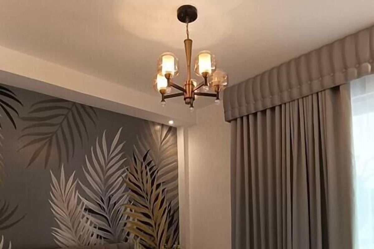 Un dormitorio moderno con una cama grande, una araña, una planta y vistas al exterior.