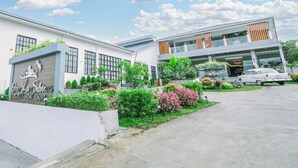 Un hôtel au design moderne, doté d’une grande enseigne, d’un jardin bien entretenu et d’un bâtiment à deux étages avec un balcon.