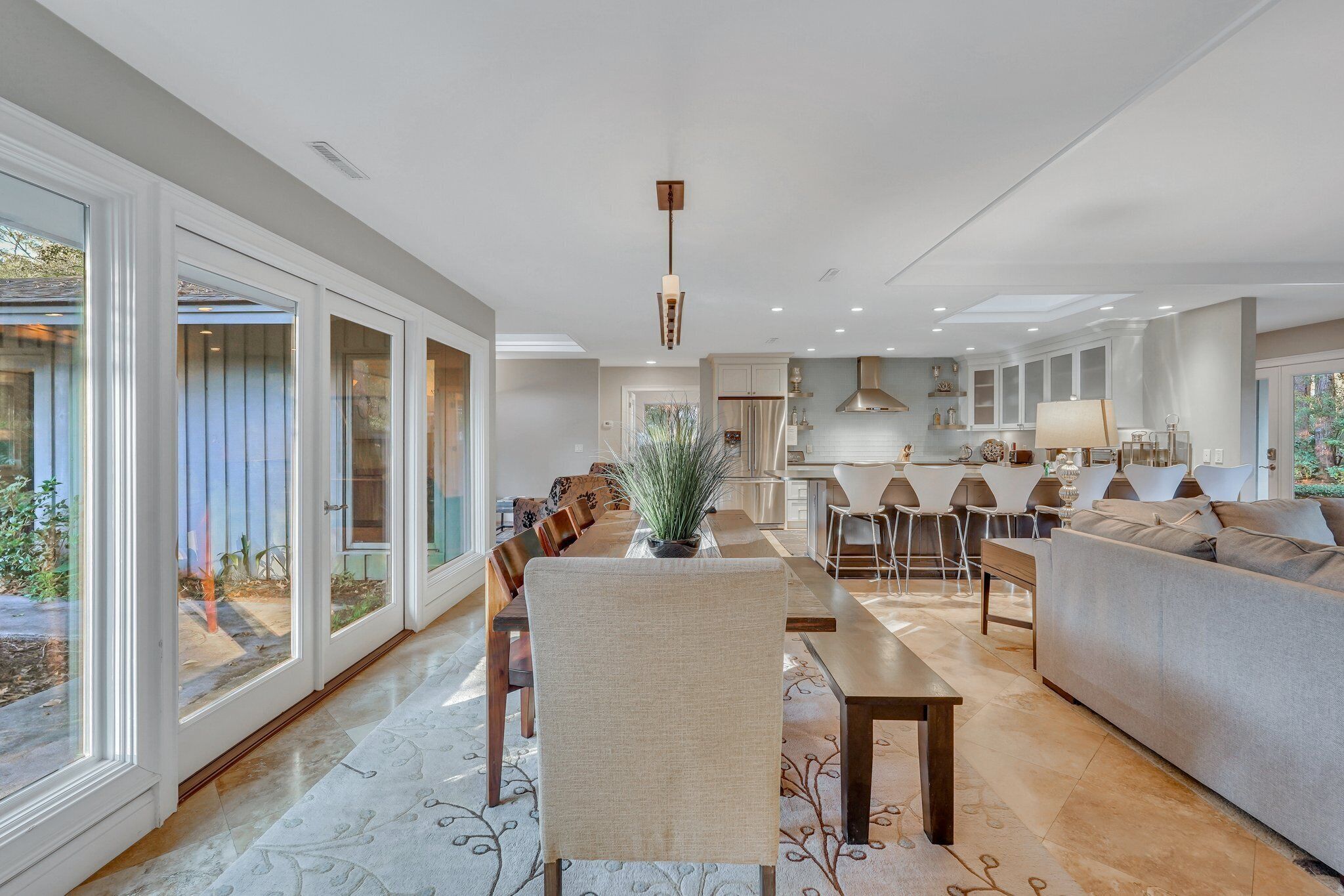 A modern open-plan living area with a dining table, sofa, and kitchen in the background.