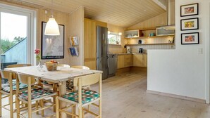Una cocina moderna con armarios de madera, un refrigerador de acero inoxidable y un comedor con mesa y sillas.
