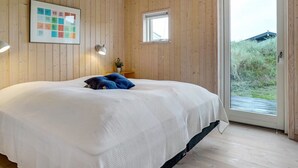 Un dormitorio con una cama grande, paredes de madera, un ventanal pequeño y vistas al exterior.