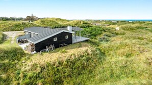 Una casa moderna con techo plano, terraza y vista al mar.