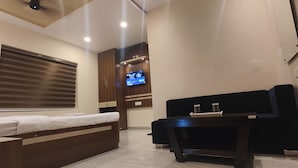 A modern hotel room with a bed, a small desk, a television, and a coffee maker. - Hotel Jayadeep  (Bhubaneshwar)