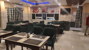 A restaurant with green upholstered chairs, marble flooring, and a ceiling with blue lighting. - Hotel Jayadeep  (Bhubaneshwar)