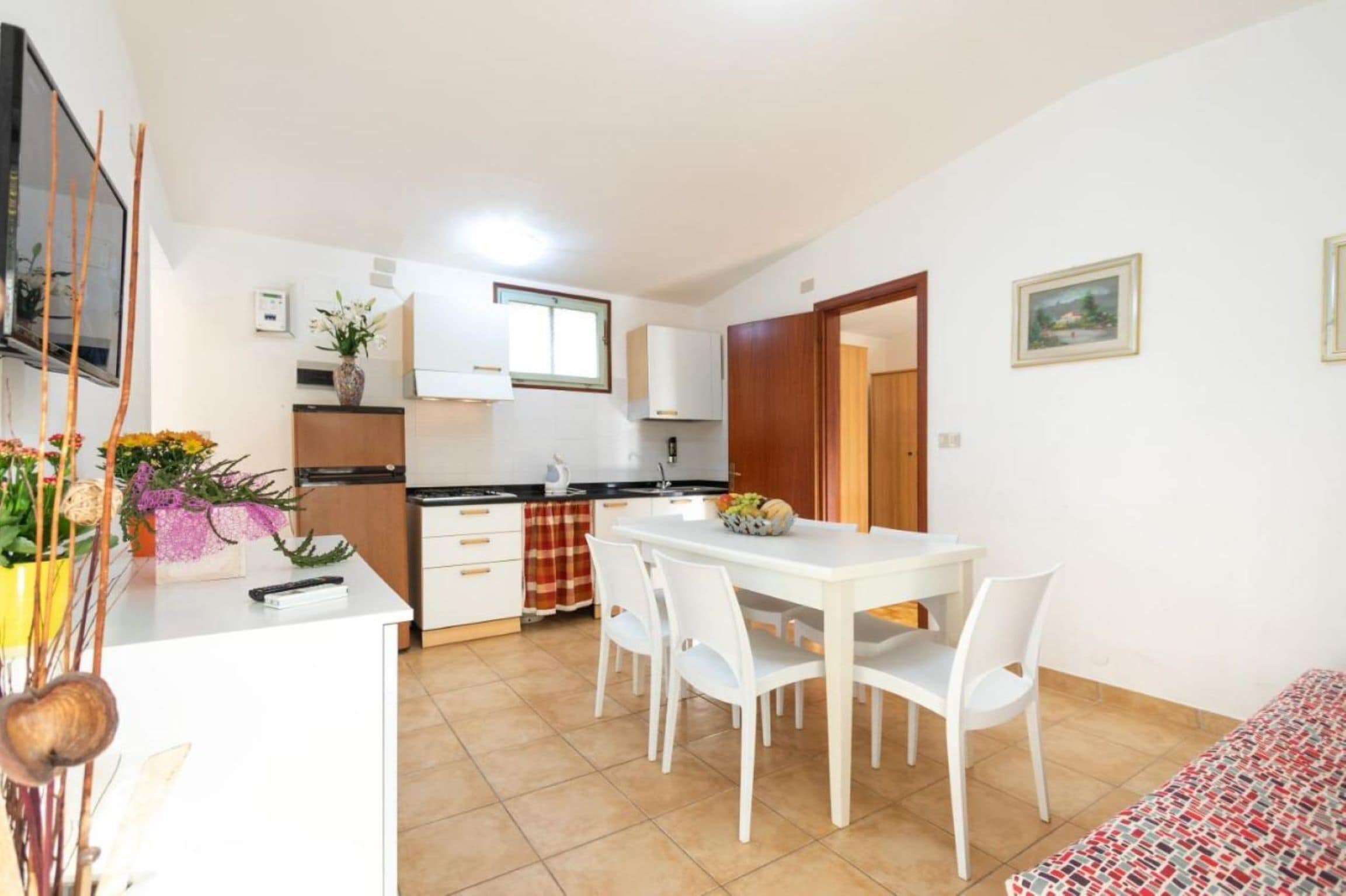 A compact kitchen with white cabinets, a dining table with chairs, and a small window.