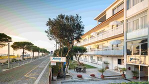Un hôtel situé au bord de l’eau, doté d’une terrasse, d’une enseigne indiquant « Sports nautiques » et offrant une vue sur la mer.