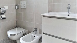 A modern bathroom with a toilet, bidet, and sink. - Stunning Villa-beahost (Lignano Sabbiadoro)
