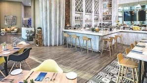 A modern restaurant with a bar area, wooden flooring, and a mix of bar stools and dining tables.