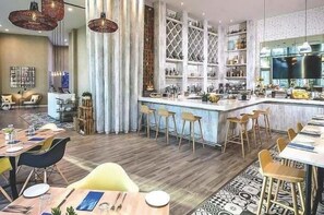 Un restaurante moderno con zona de bar, suelo de madera y una combinación de taburetes y mesas para comer.