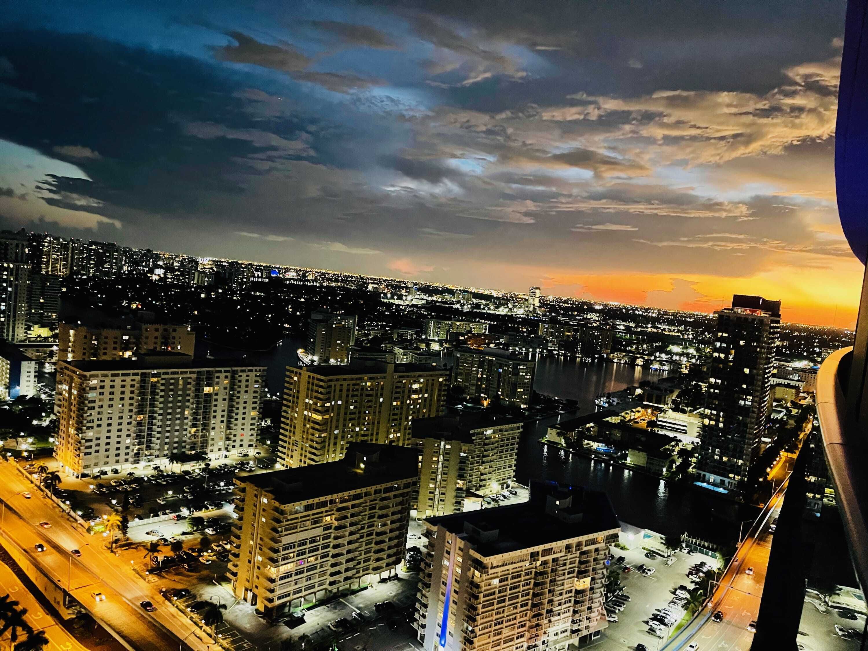 Une vue nocturne d’une ville, avec ses gratte-ciel et une rivière.