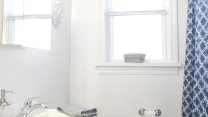 A bathroom with a white sink, a toilet, and a window above the toilet. - 6647 1W | Quaint Studio in Central St. Louis (St. Louis)