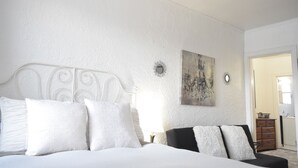 A bedroom with a large bed, a dresser, and a painting on the wall. - 6647 1W | Quaint Studio in Central St. Louis (St. Louis)