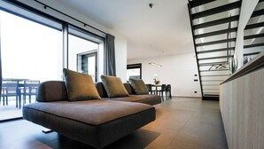 Una sala moderna con un conjunto de sofás, un comedor y una escalera.