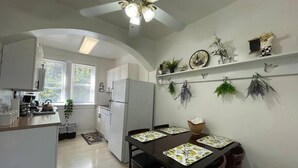 A modern kitchen with white cabinets, a refrigerator, and a dining area with a table set for four. - 6653 1N | European Style Unit Near Forest Park (St. Louis)