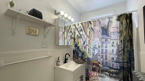 A bathroom with a sink, mirror, and a wall mural depicting a street scene. - 6653 1N | European Style Unit Near Forest Park (St. Louis)
