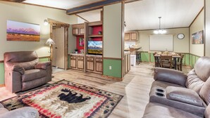 Un salon spacieux avec un grand canapé en cuir, un tapis à motifs et un coin repas comprenant une table et des chaises en bois.