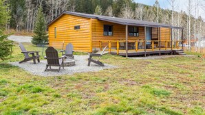 Une cabane en rondins dotée d’un porche et d’un espace extérieur aménagé pour s’asseoir.
