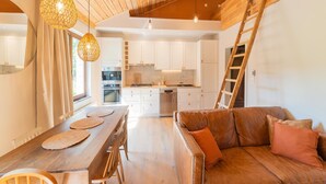 Una cocina moderna con armarios blancos, una mesa de comedor de madera con individuales y un sofá de cuero.