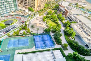An aerial view of a hotel complex with multiple tennis courts, lush landscaping, and modern buildings.