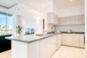 A modern kitchen with a large island, white cabinetry, and a city view through large windows.