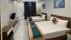 A modern hotel room with a central bed, a smaller bed, a desk with a computer, and a TV. - Homestay the Sun Grand World (Phu Quoc)