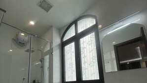 A modern bathroom with a glass shower enclosure, a toilet, a bidet, and a sink with a mirror above. - Homestay the Sun Grand World (Phu Quoc)
