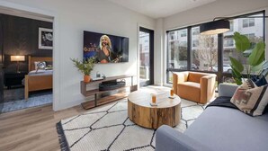 A modern living room with a sofa, coffee table, TV, and large windows.