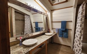 Une salle de bain avec un grand miroir, un lavabo et un porte-serviettes.