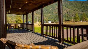 A wooden deck with a view of a mountainous landscape. - The Kabins - Camp Misery (Columbia Falls)