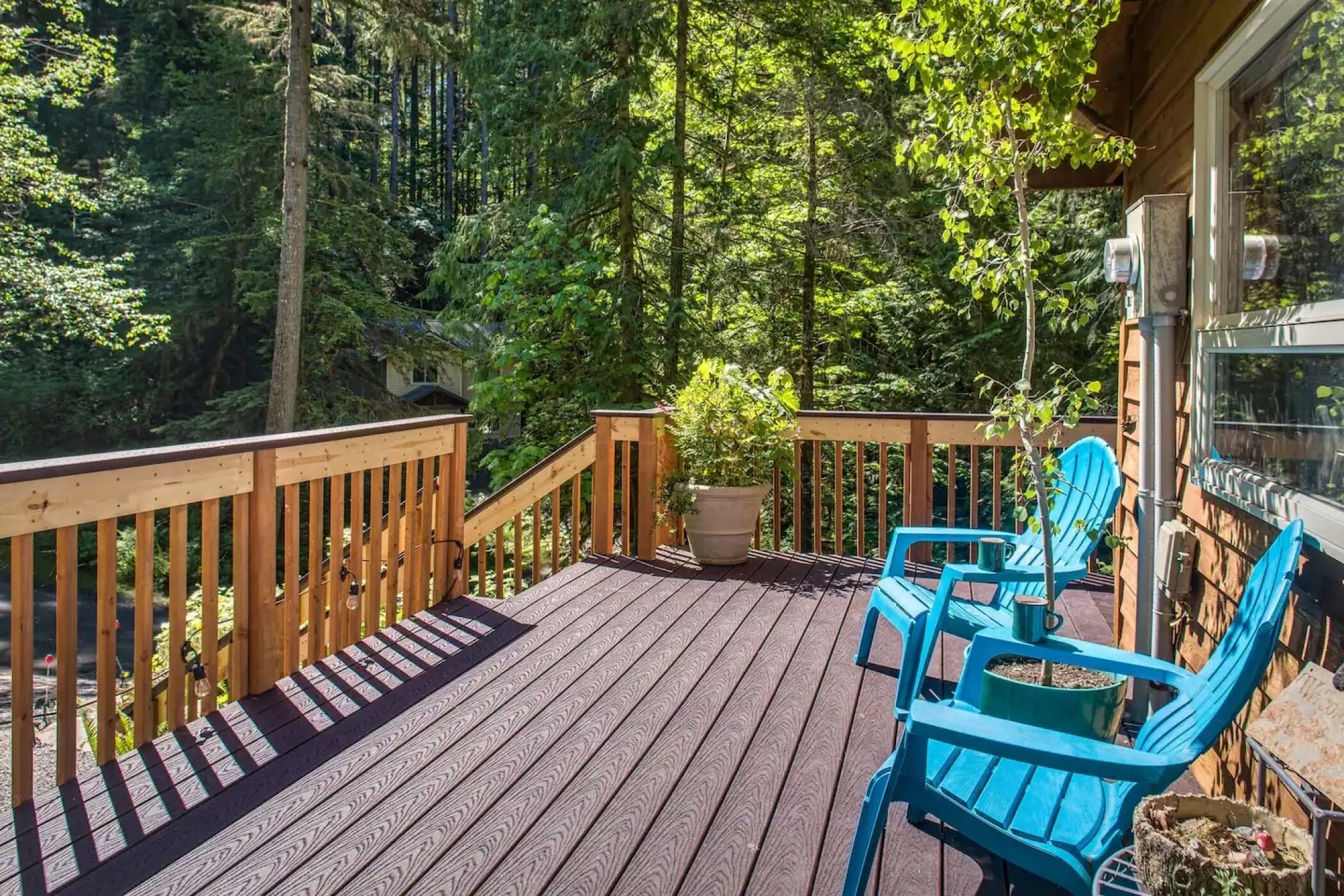 Eine Holzterrasse mit blauen Stühlen und einem Blumentopf.