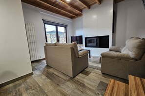 A modern living room with two sofas, a TV, and a fireplace.