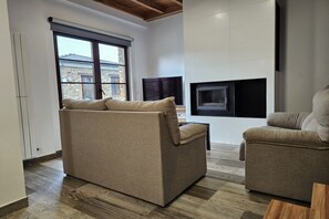 A modern living room with a sofa, a fireplace, and a television.