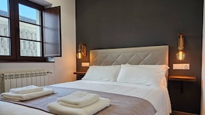 Een slaapkamer met een groot bed, twee bedlampen, een raam en een radiator.