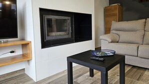 Een moderne woonkamer met een flatscreen televisie, een open haard, een houten kast en een beige bank.