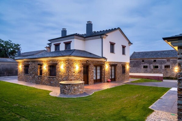 A two-story house with stone exterior walls, a stone fireplace, and a well-maintained lawn.