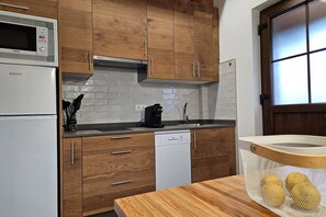 A kitchen with wooden cabinets, a white refrigerator, a microwave, a coffee maker, and a dishwasher.