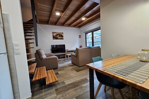 A modern living room with a sofa, TV, and wooden flooring.