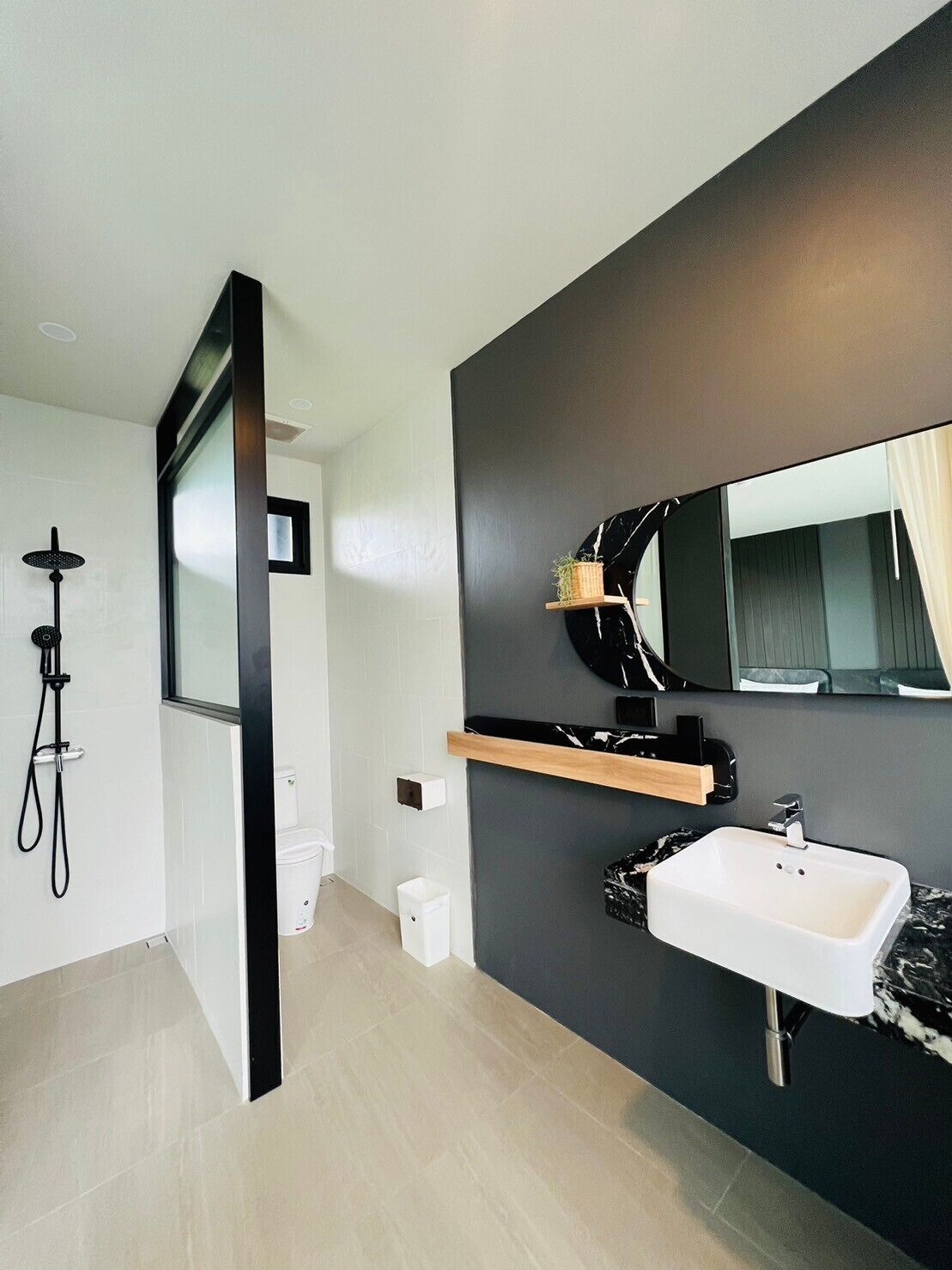 A modern bathroom with a large mirror, a sink, and a shower.