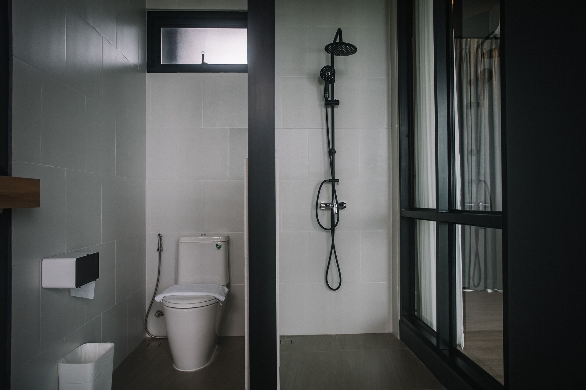 A modern bathroom with a toilet, a shower, and a window.