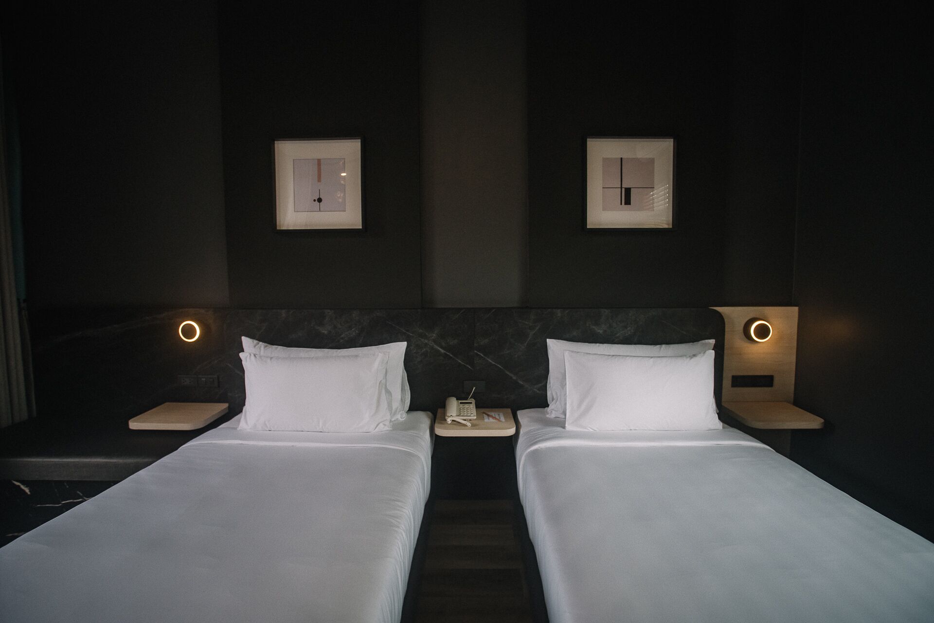 A hotel room with two beds, each with white linens, and bedside tables with lamps.