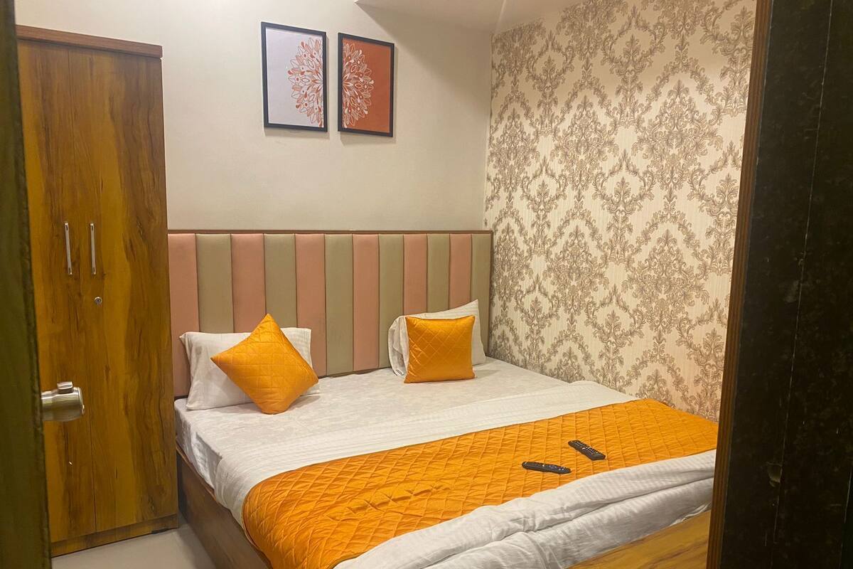 Un dormitorio con cama, dos almohadas, cabecera de madera, armario de madera y una puerta.