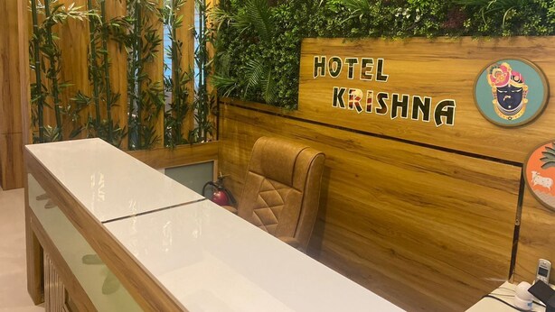 Ein Empfangsschalter mit einem Holzkopfteil, beschriftet mit 'HOTEL KRISHNA', und einem bequemen Sessel.