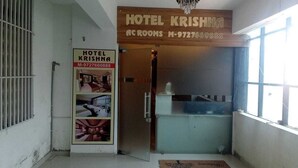 Der Eingang zum Hotel Krishna mit einem hölzernen Schild, einer Glastür und einem Fenster zur rechten Seite.