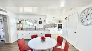 A modern kitchen with white cabinets, a granite countertop, and a large clock on the wall.