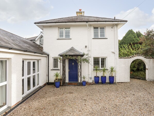 A two-story house with a blue door, white walls, and a gravel driveway. - Bwthyn (Porthmadog)