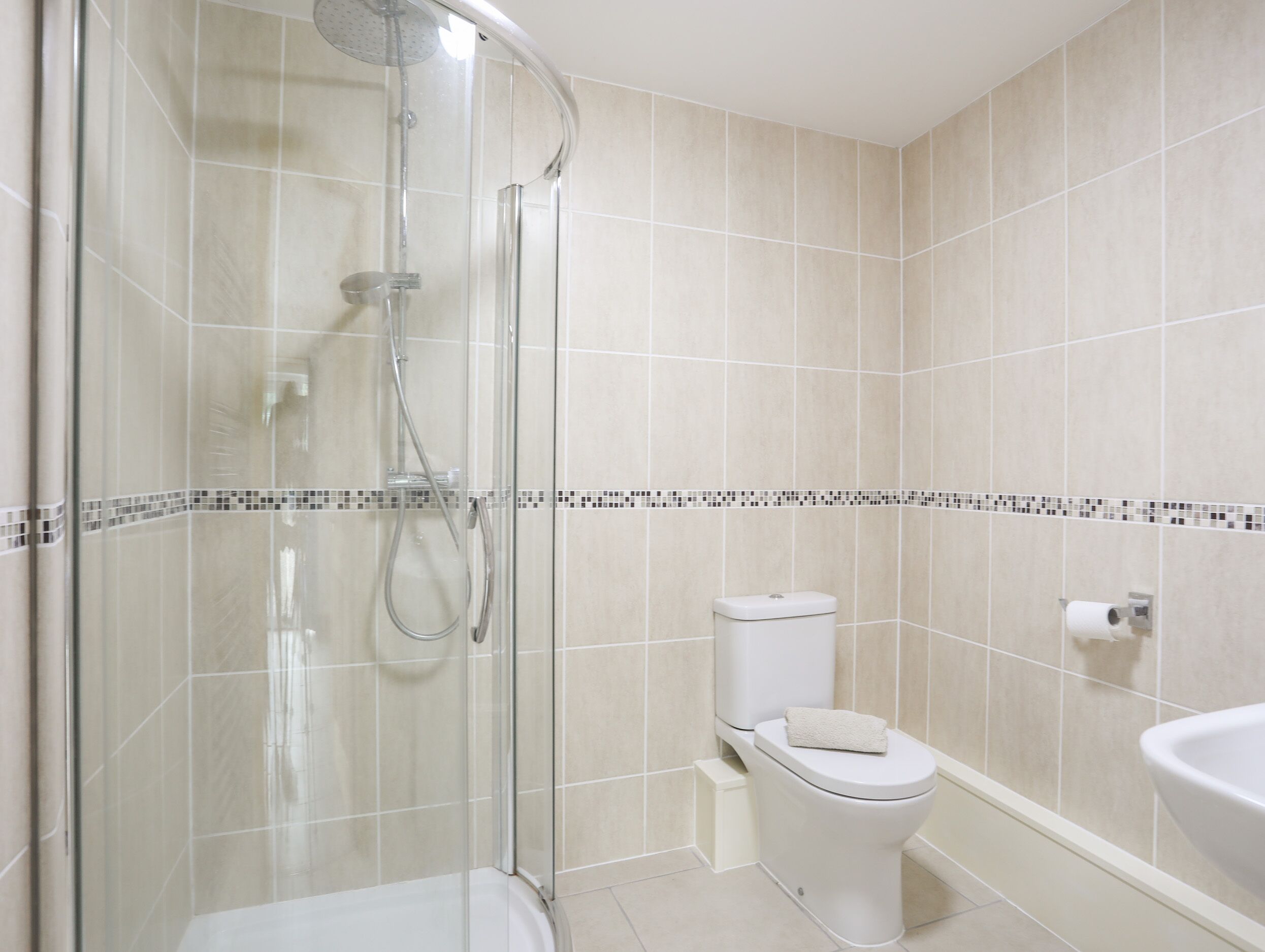 Un bagno moderno con doccia vetro, servizi igienici e lavabo.