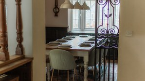A dining area with a long table set for multiple people, a chair, and a decorative metal gate. - Grey Walls (Penrith)