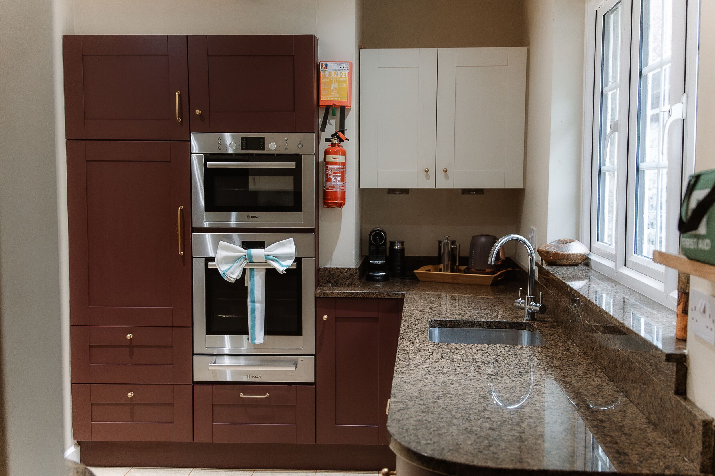 Una cocina con gabinetes marrón oscuro, electrodomésticos de acero inoxidable, encimera de granito y ventana que proporciona luz natural.