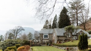 A stone house with a well-maintained lawn and a stone staircase leading to the entrance. - Grey Walls (Penrith)