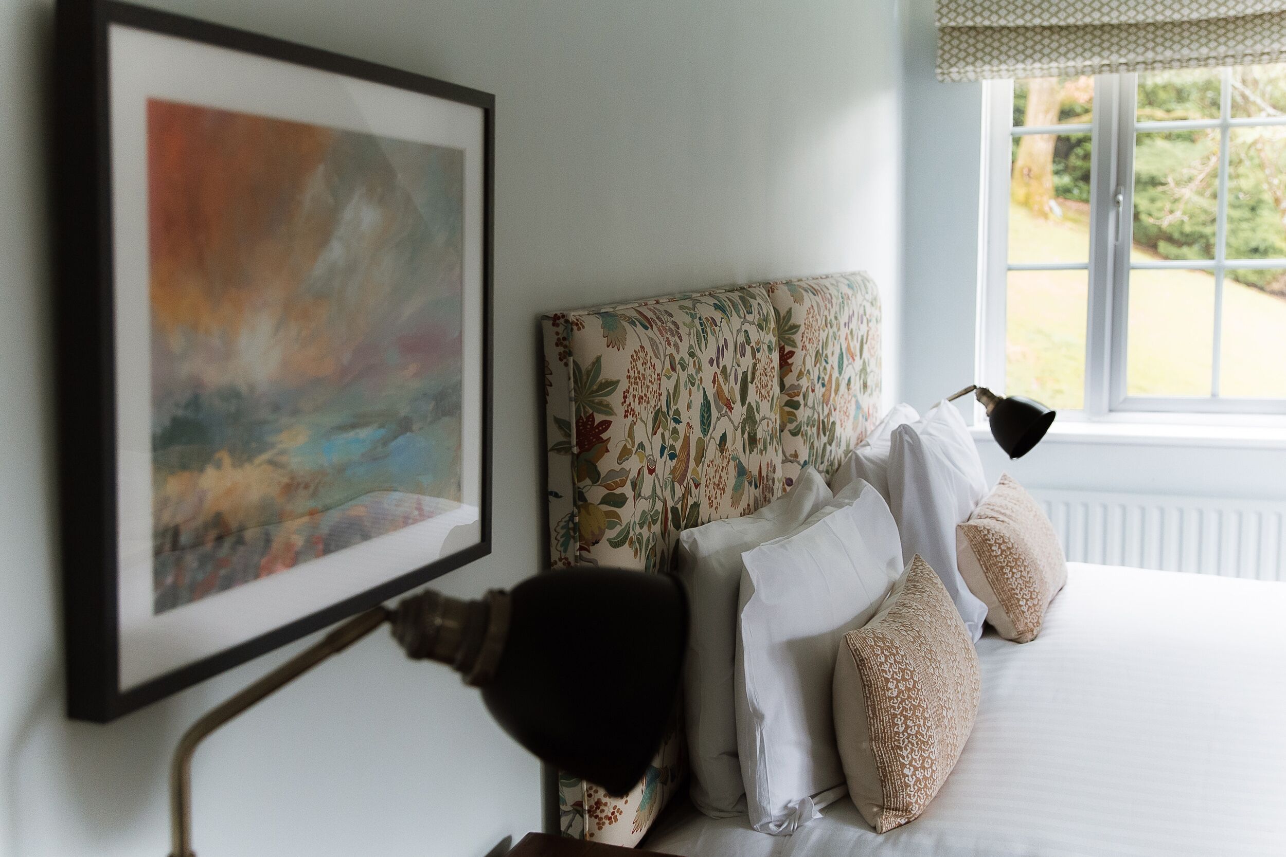 Un lit bien fait, agrémenté d’oreillers à motifs et d’un tableau abstrait encadré accroché au mur.